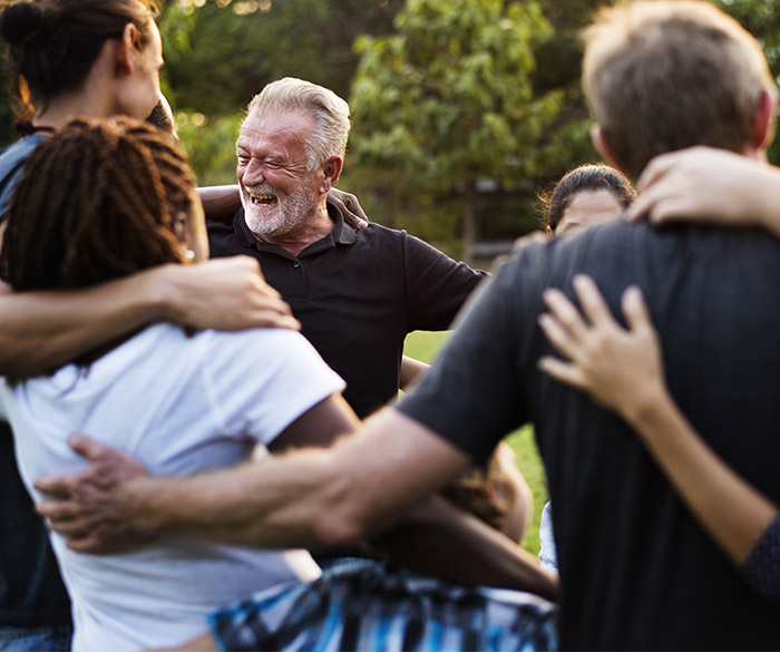 A happy senior man dancing in a circle with a group of people